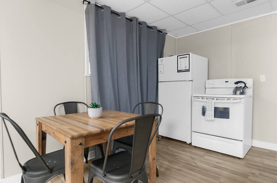 From this angle, the dining area seamlessly connects the downstairs living space to the kitchen, offering a functional yet inviting setup. It's an ideal spot to sit, share a meal, and stay connected to the heart of the space.