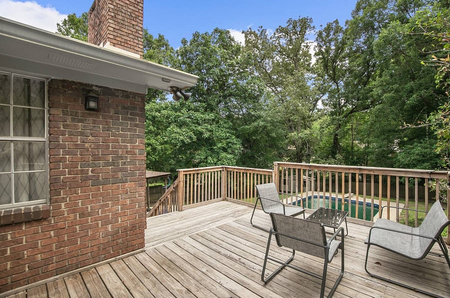 Tucked beneath the covered porch, the seating area provides a cozy place to unwind, offering a balance of comfort and fresh air just steps from the backyard and pool.