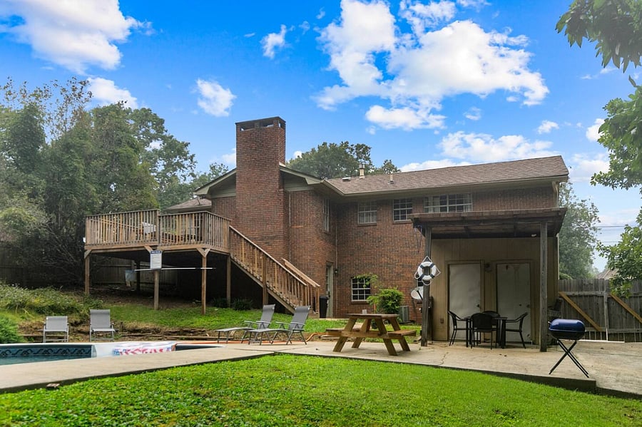 From the back of the home, take in the inviting outdoor setup-an awning-covered seating area offers shade and comfort, creating the perfect spot to relax while overlooking the peaceful, private yard.
