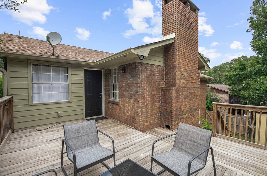 Tucked beneath the covered porch, the seating area provides a cozy place to unwind, offering a balance of comfort and fresh air just steps from the backyard and pool.