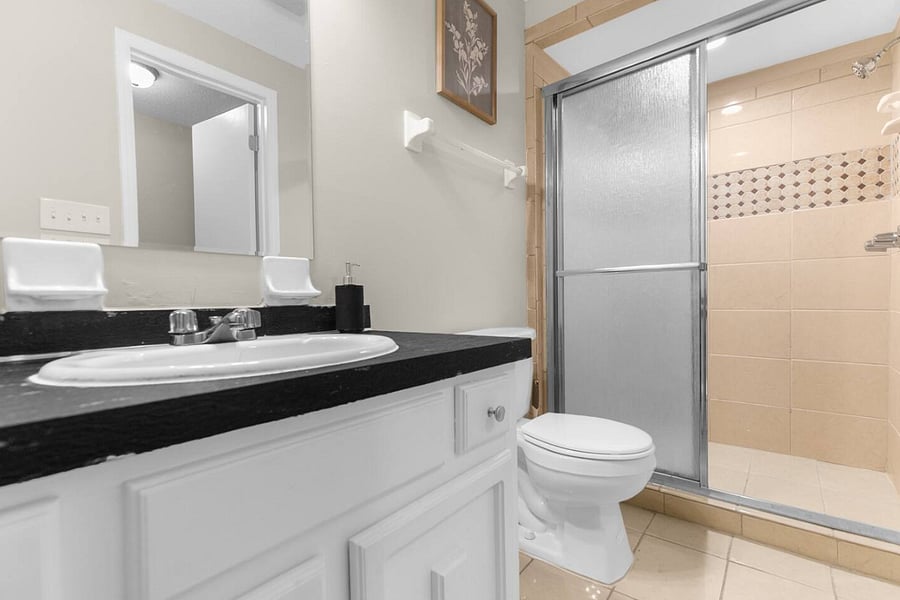 The downstairs full bathroom features a clean, modern walk-in shower, offering a refreshing space to start or end your day. Stocked with fresh linens and essential supplies, it's designed for both comfort and convenience.