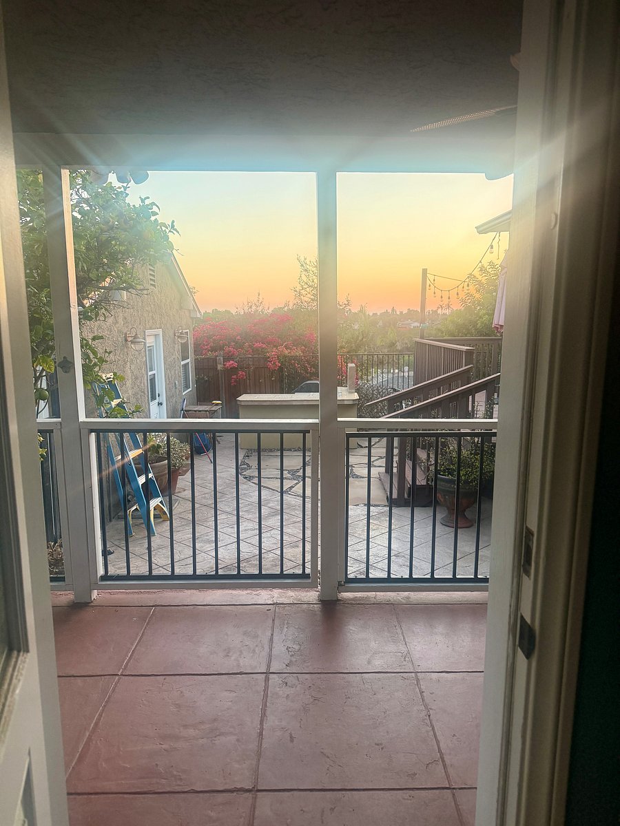 View from the bedroom door looking over the patio to the shared backyard with BBQ and deck for entertaining.
