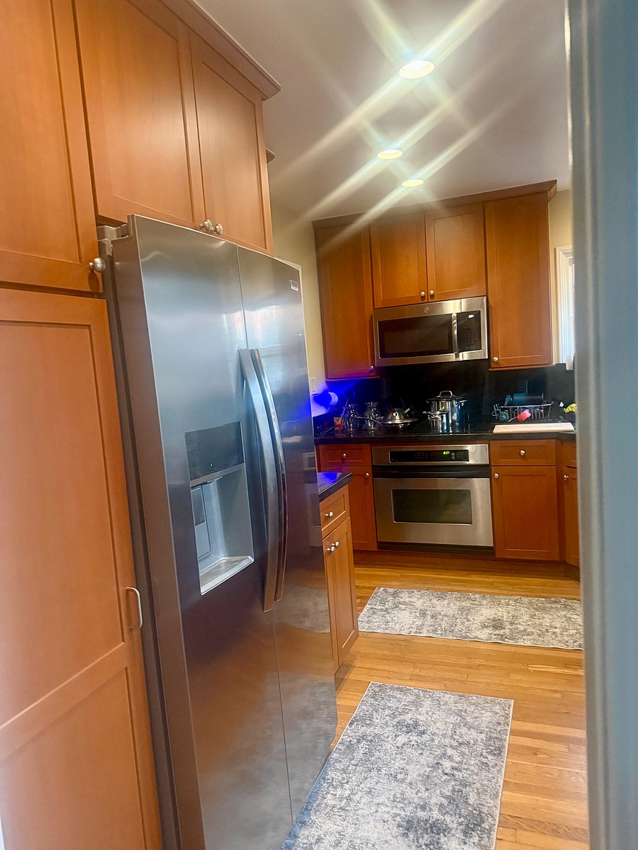 View of kitchen off the laundry room. Refrigerator, microwave, stove, dishwasher, coffee maker and air fryer.