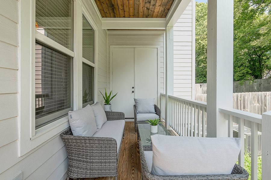 Private covered porch just off of the living room with outdoor furniture, leading into the fenced-in backyard.