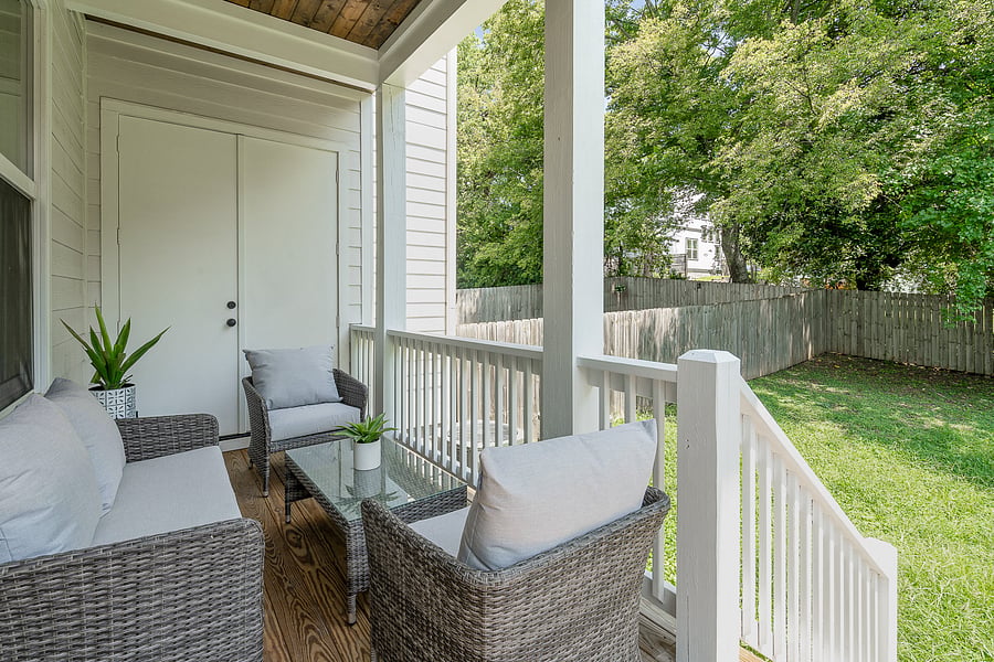 Private covered porch just off of the living room with outdoor furniture, leading into the fenced-in backyard.