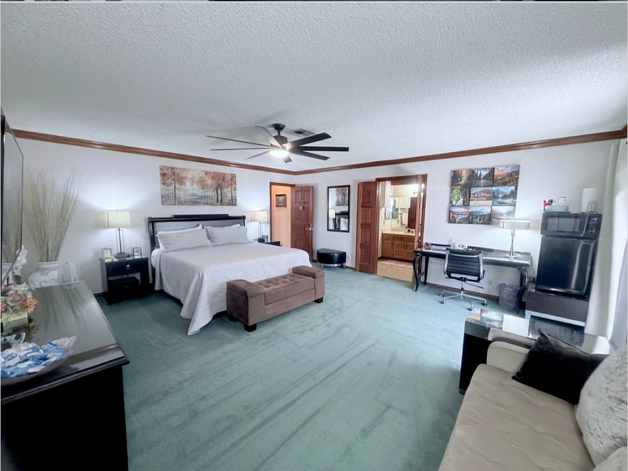 Massive 425 sqft primary suite featuring a comfortable king - size bed, a private sofa seating area, a 55" smart TV, private en-suite bathroom,walk-in closet, dedicated desk workspace.