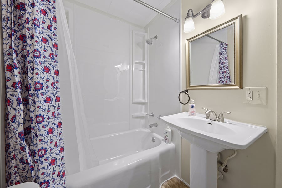 Clean, bright bathroom equipped with a full tub/shower combination, and generous storage.