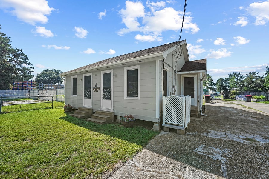 Convenient side access with ample off-street parking, surrounded by green grass and sunny skies.