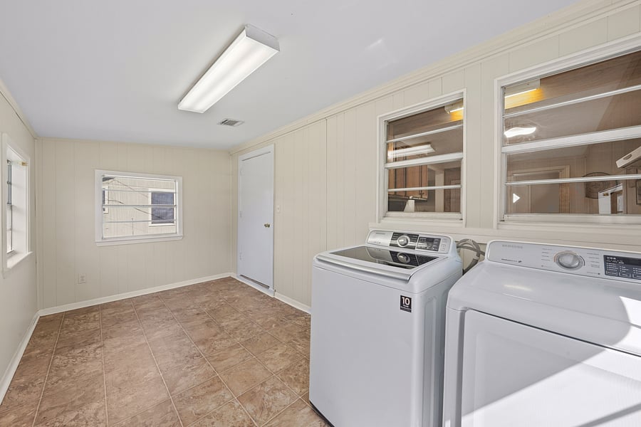 Convenient in-unit laundry room featuring a top-load washer and extra storage space.
