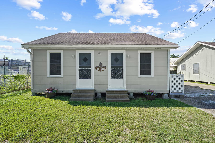 Charming exterior  with classic Cajun cottage featuring double doors. .