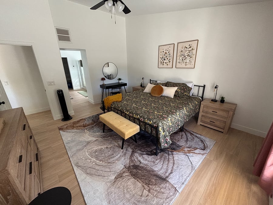 Primary bedroom with King bed and ensuite bathroom includes mounted smart tv, private desk, dressers, walk-in closet, and all the quality bedding of home!
