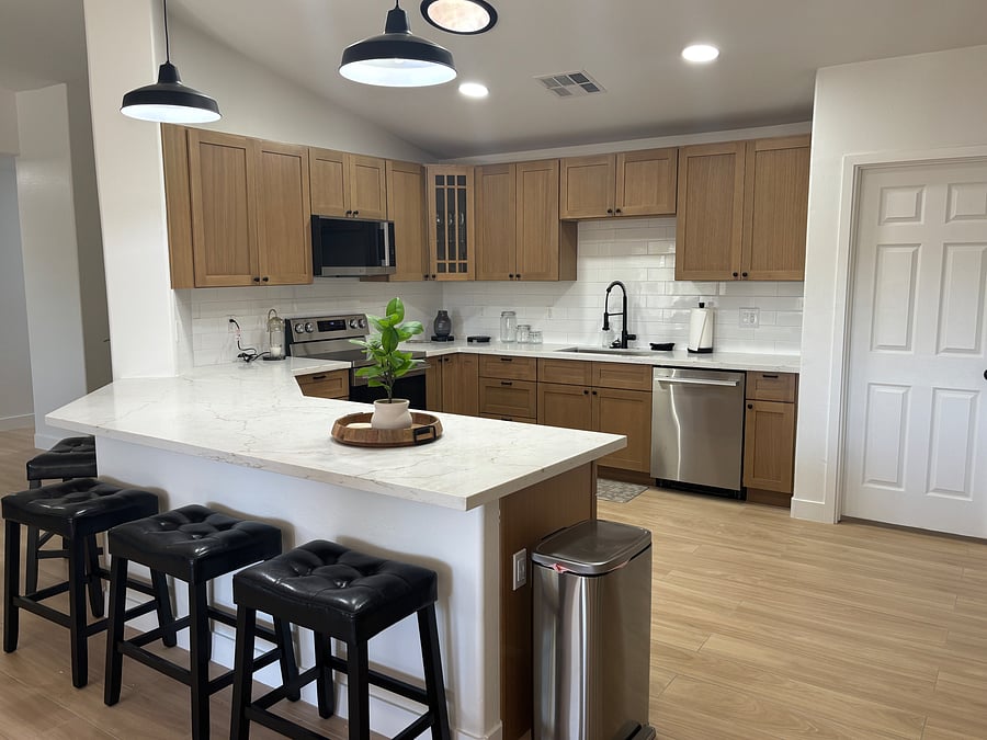 Beautifully remodeled kitchen with warm oak cabinetry, quartz counters, stainless steel appliances and stocked cooking/serving supplies including gorgeous coffee bar