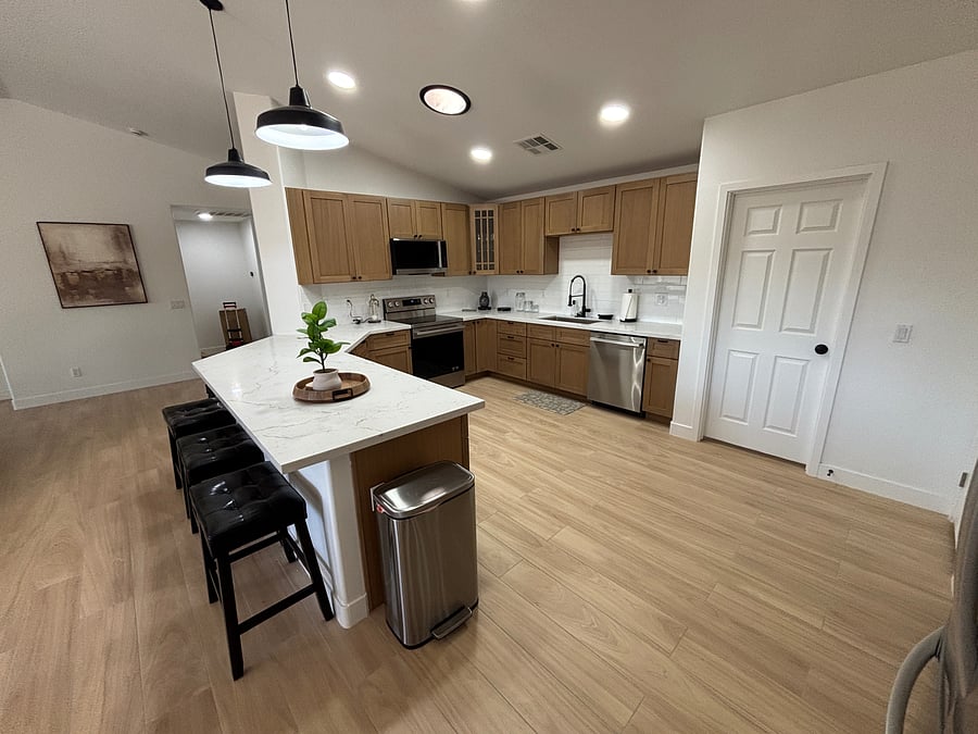 Beautifully remodeled kitchen with warm oak cabinetry, quartz counters, stainless steel appliances and stocked cooking/serving supplies including gorgeous coffee bar