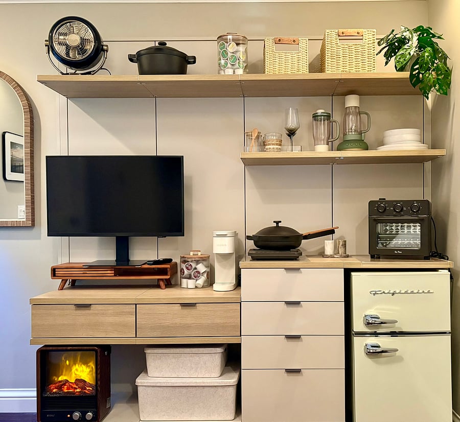 Fully equipped kitchenette station paired with a smart TV setup, retro mini fridge, coffee maker, and ambient fireplace heater.