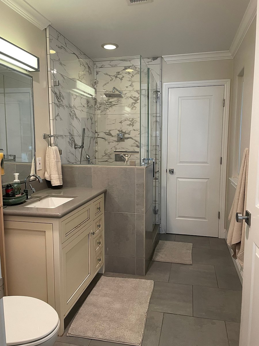 Modern en-suite bathroom featuring a walk-in tile and glass shower, large vanity, and fresh towels provided.