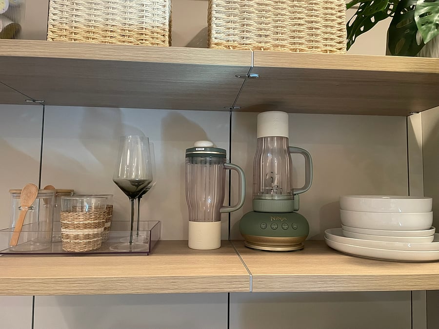 Open shelving stocked with essentials, including a Ninja blender for morning smoothies, glass overnight-oat jars, glassware, dishes and extra storage.