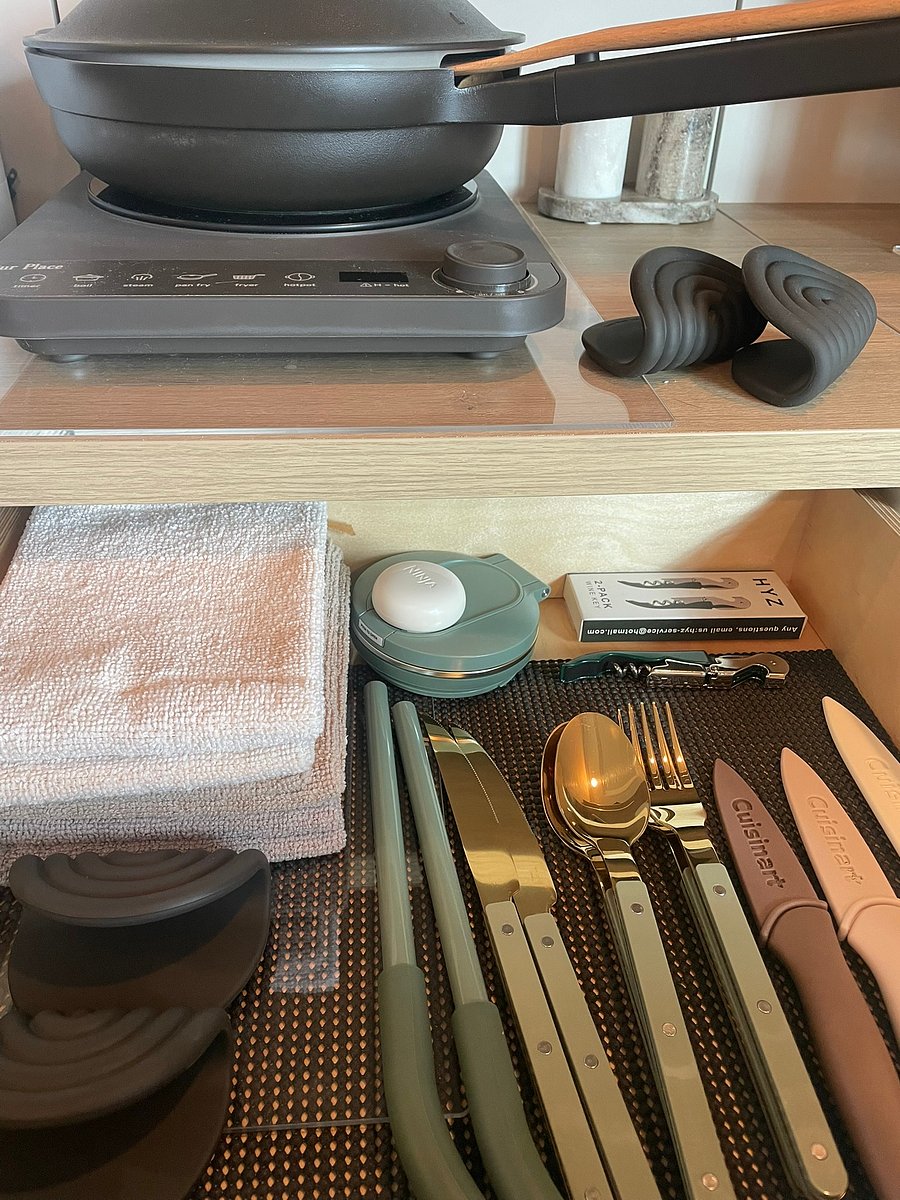 Thoughtfully organized drawer stocked with utensils, cutlery, wine opener, hot pads, and fresh kitchen linens.