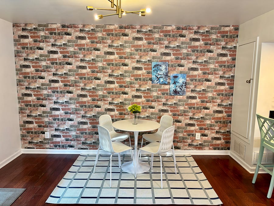 Stylish dining space with a Tulip dining set, geometric rug, and accent brick feature wall.