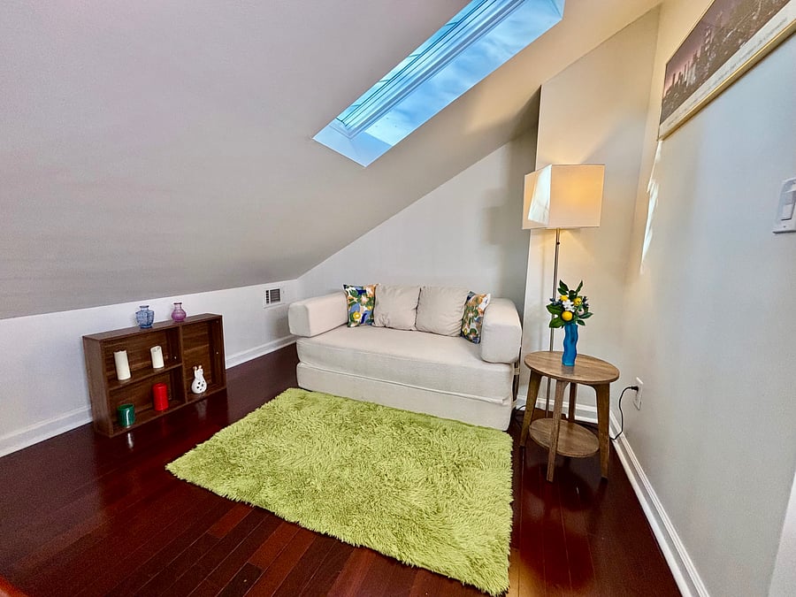 Cozy upstairs reading nook featuring skylight natural lighting and comfortable seating.