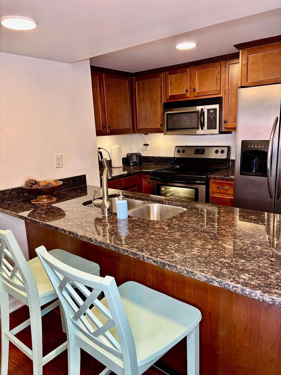 Fully equipped kitchen featuring granite countertops, stainless steel appliances, and breakfast bar seating.