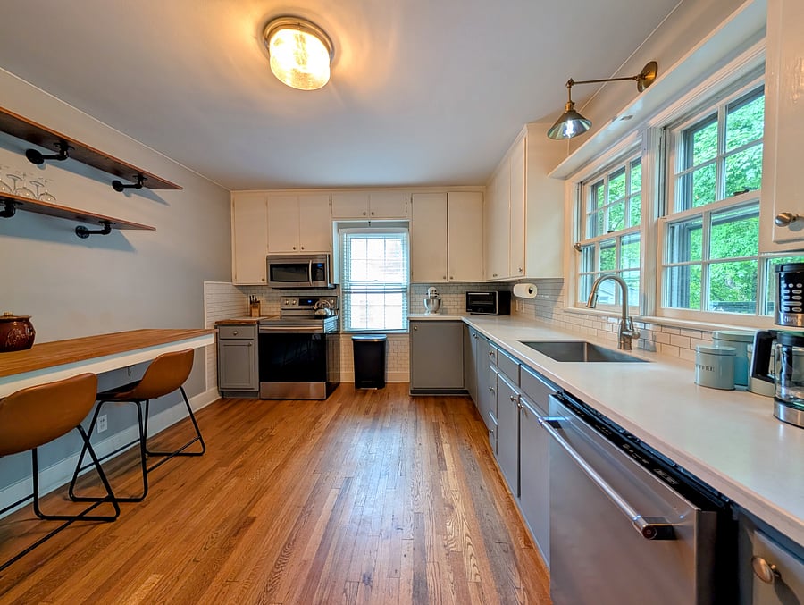 Large kitchen with bar top seating, Kitchen-aid stainless steel appliances, cookware, tableware and utensils.