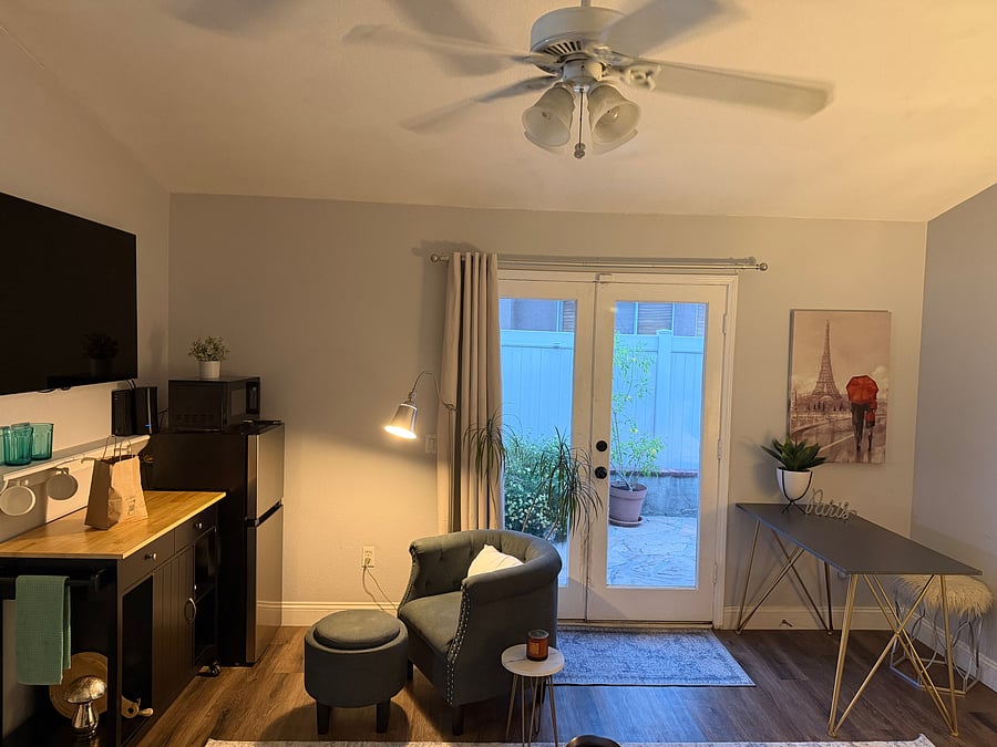 Entry door (French doors) with keyed entry, kitchenette cabinet, Smart TV, chair and ottoman, light, and table/ desk and stool.