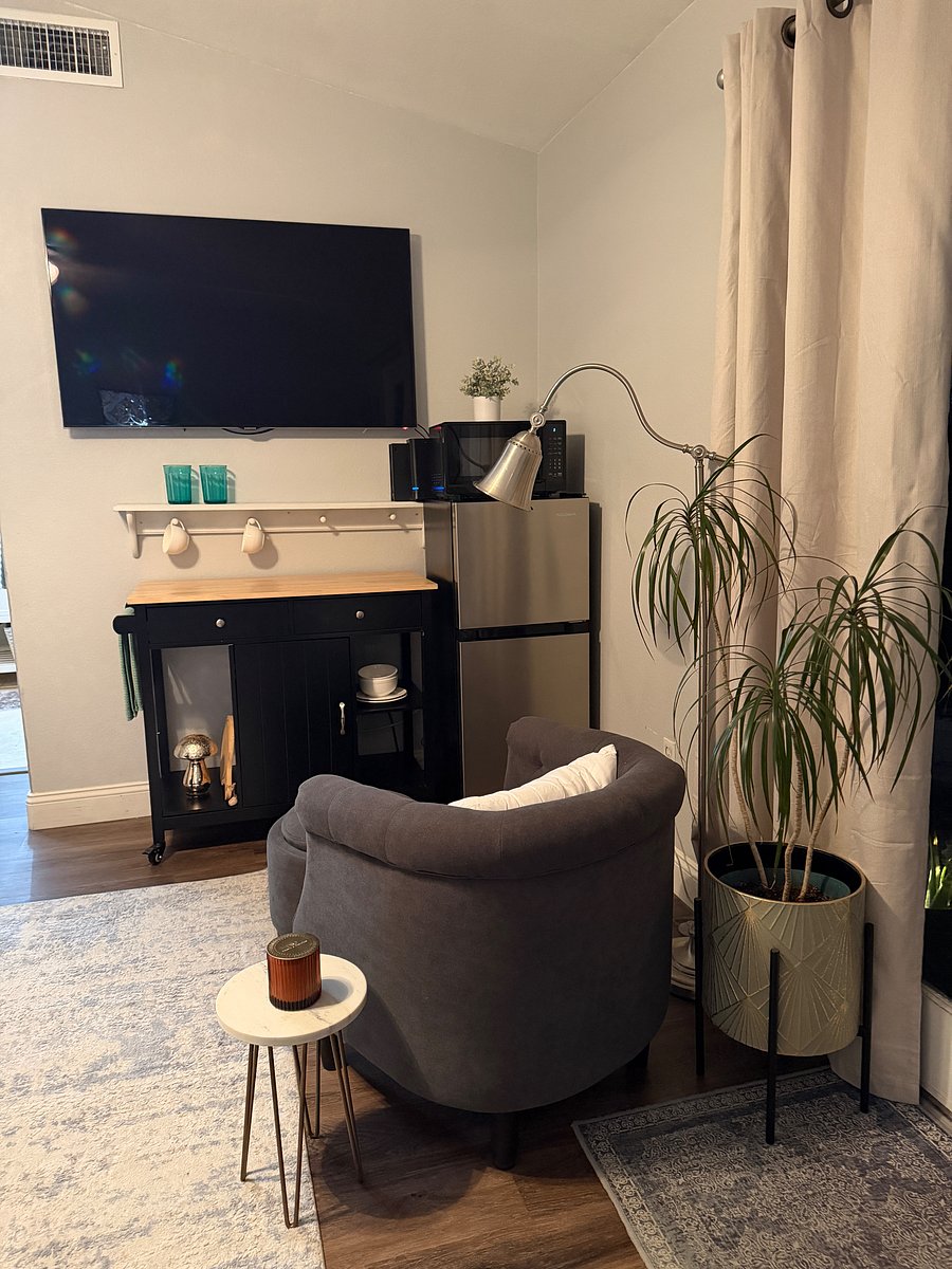 Smart TV with Prime stick, cozy chair and ottoman with storage, side table, lamp, microwave, small refrigerator, WiFi, kitchen cabinet with dish towel, 2 plates, 2 bowls, 2 cups, 2 mugs and 2 sets of silverware.
