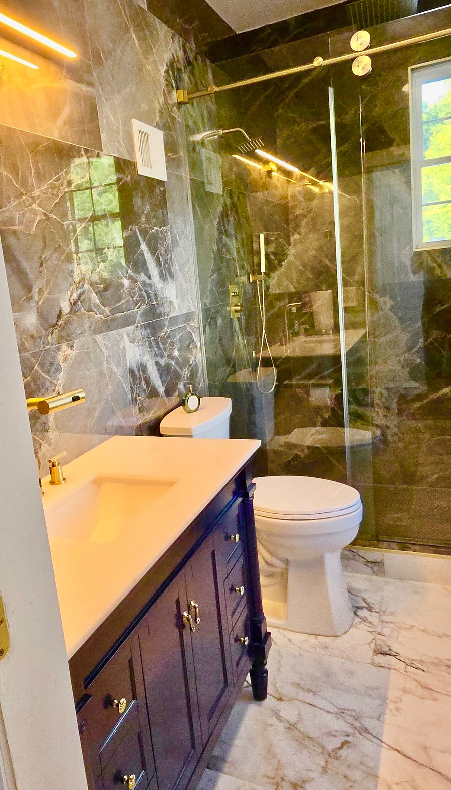 The home has a downstairs bath completed with premium finishes, custom ceramic tile from the floor to the ceiling and custom everything, complete with brushed gold fixtures.