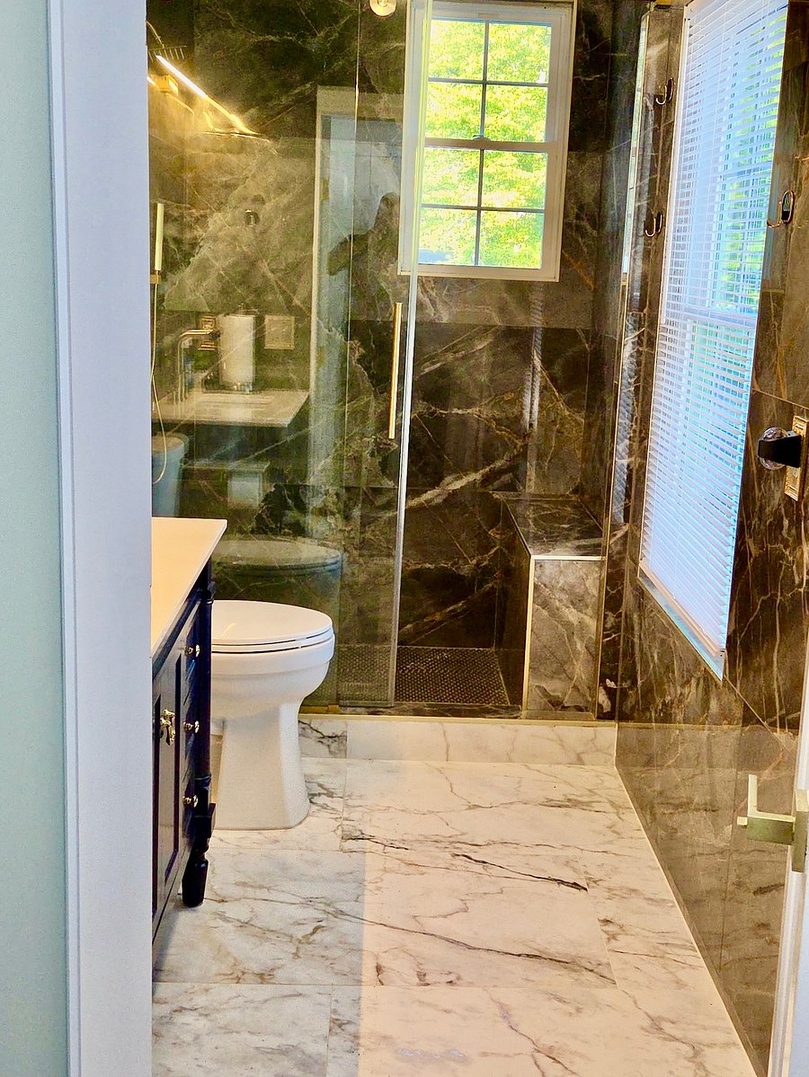 The home has a downstairs bath completed with premium finishes, custom ceramic tile from the floor to the ceiling and custom everything, complete with brushed gold fixtures.