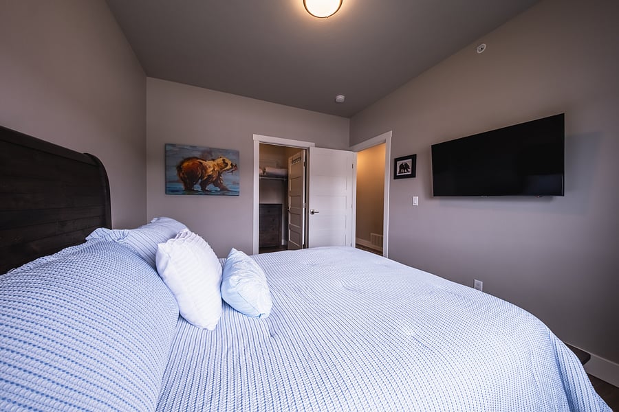 Guest bedroom featuring queen size bed, walk-in closet and TV.