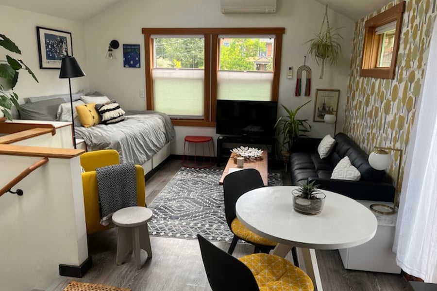 Open floor plan studio with living and sleeping area, small table for working and dining. Cozy, private, and cheery. Front windows face driveway with leafy views of street