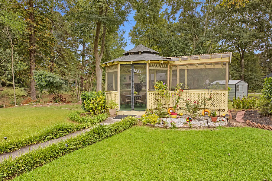 Screened gazebo surrounded by flowers, available to renters by arrangement.