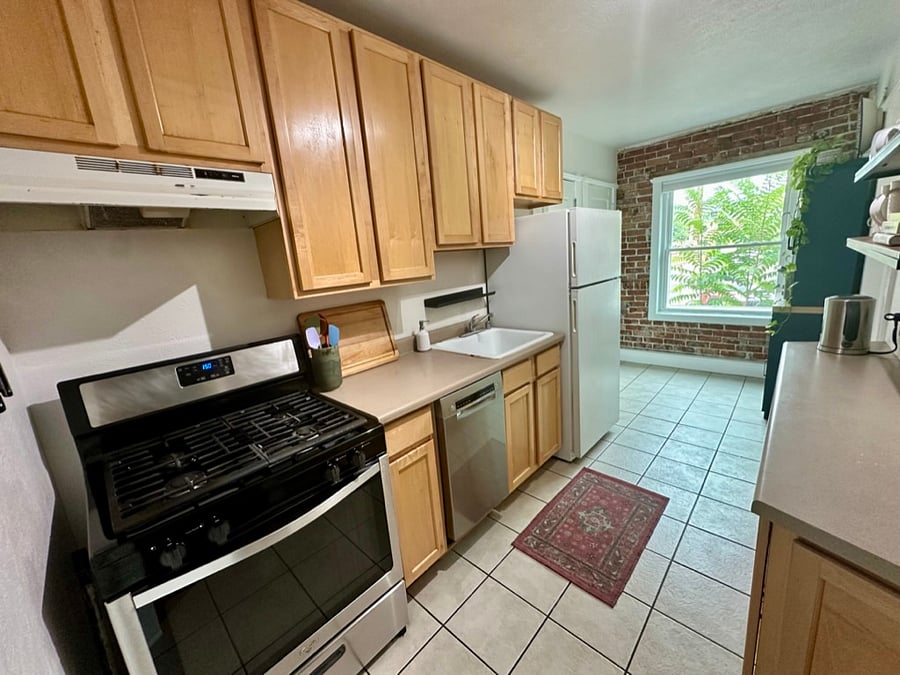 Fully equipped kitchen with exposed brick, a gas range, dishwasher, full-size refrigerator, ample cabinet and counter space, and a large pantry.