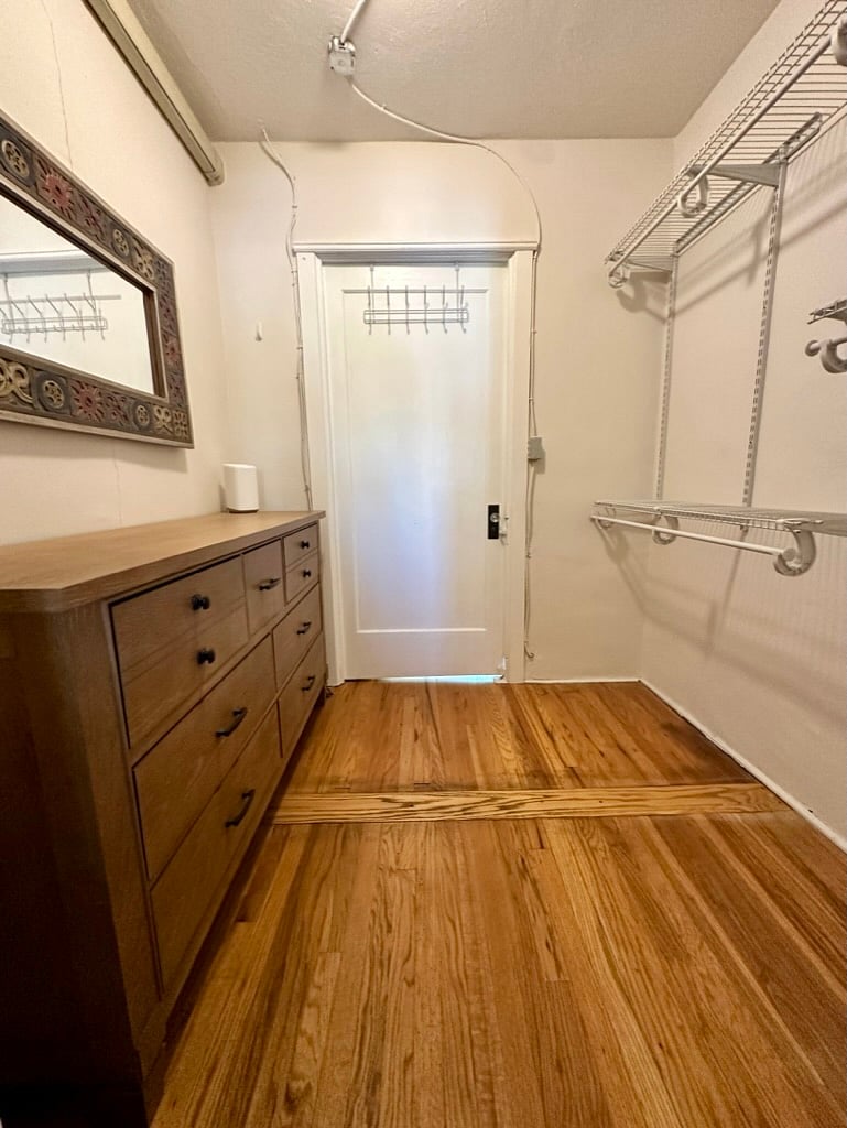 Spacious walk-in closet with built-in shelving and a dresser for plenty of clothing and storage space.