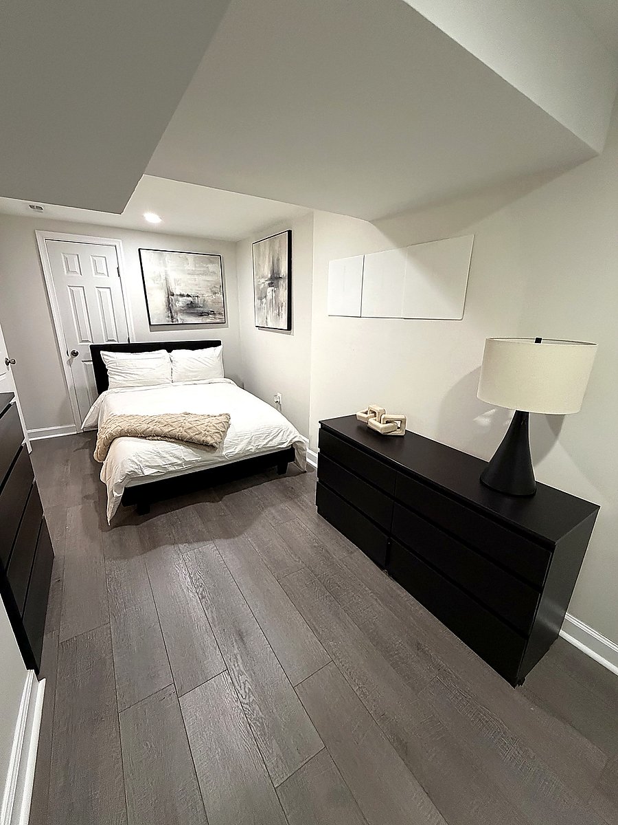Cozy private bedroom with comfortable bedding, dresser storage, and modern neutral décor.