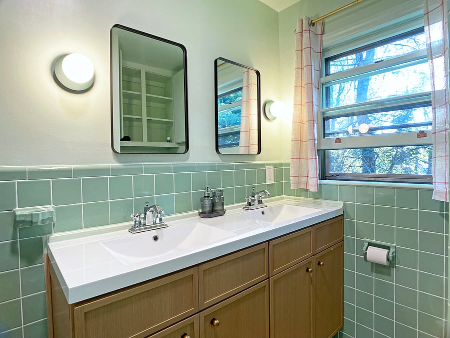 Shared bath for Bedroom 2 & 3 with double vanity and shower/tub combo. Original 1950s green tile.