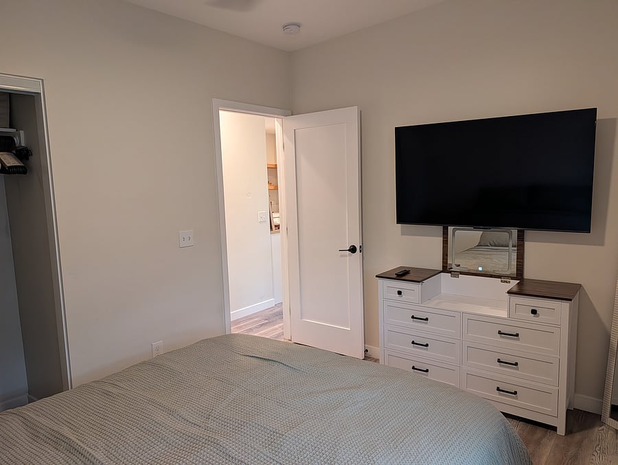 Bedroom: Dresser with vanity and TV above on swing arm.
