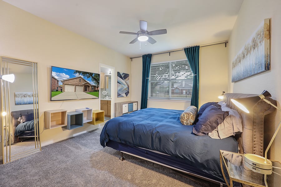 Primary bedroom with king bed, TV and ceiling fan.