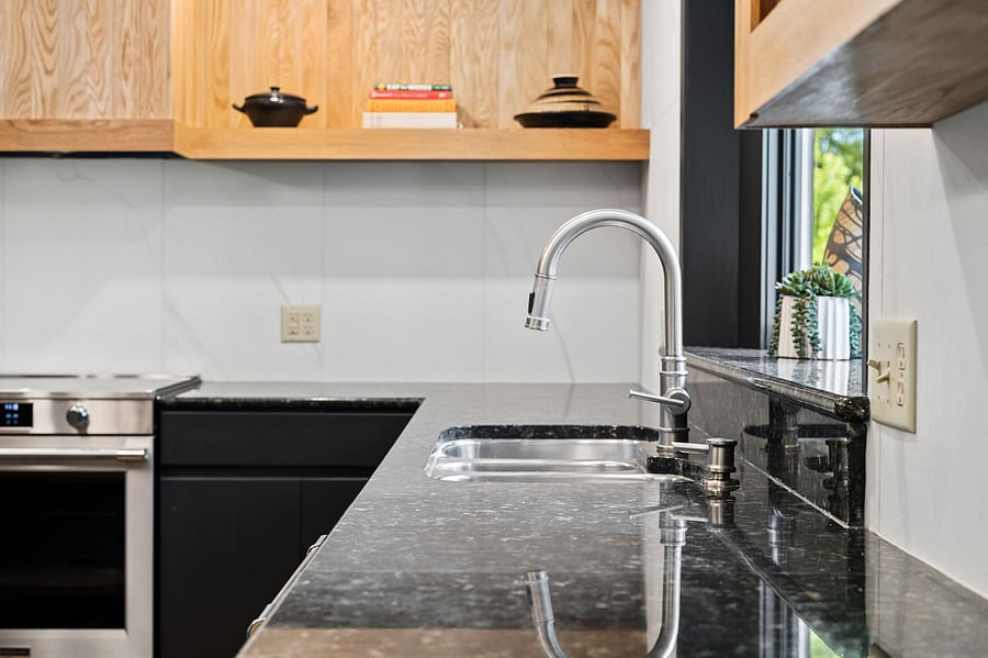 The custom kitchen was built around the home's original peacock granite countertops, paired with Italian porcelain fluted tile and custom white oak floating shelves and cabinetry.