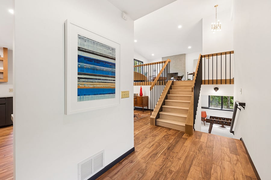 Custom white oak staircase bring Midcentury Modern vibes to the Nordic Revival. Opening the front door brings views of the living room, dining room, and lower level rumpus room with foosball table.