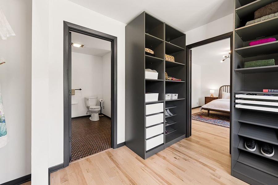The primary bedroom's large ensuite walk-in closet includes built in dressers, cabinetry, and a mix of open and drawer storage for folded clothes, shoes, and more. Connects the primary bedroom directly to the private primary bathroom.