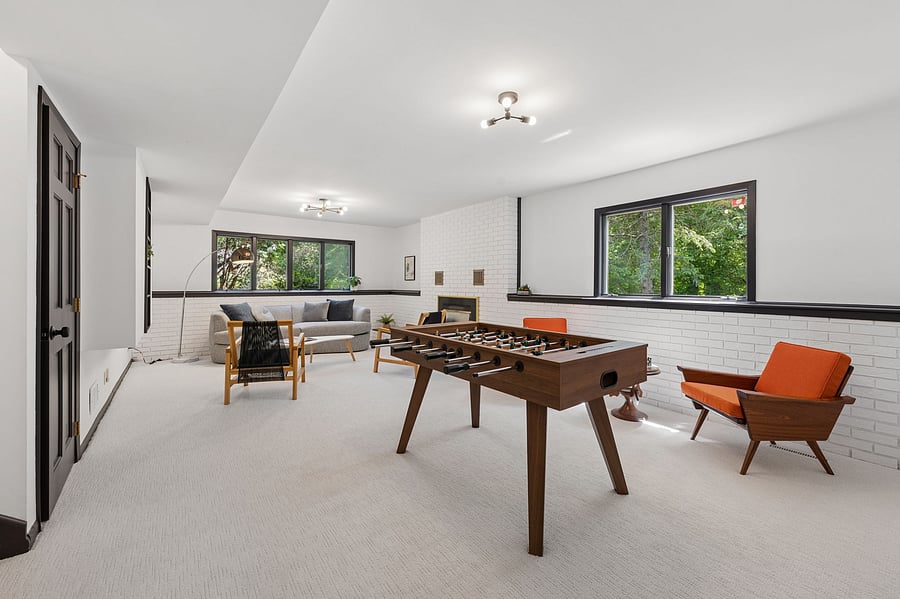 The large rumpus room / family room on the ground floor features new carpet, sunny windows with forest views, a cozy gas fireplace, and a foosball table!