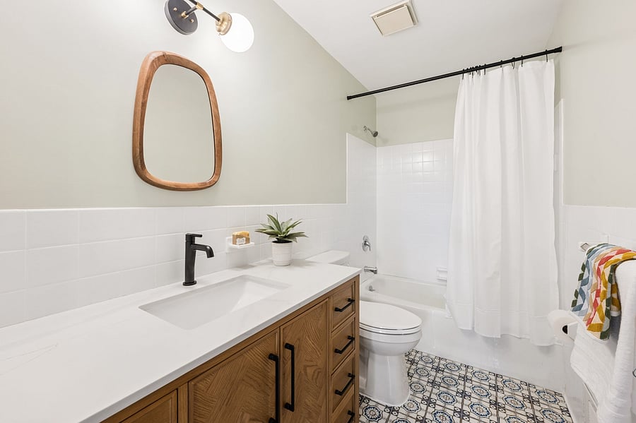 The updated third full bathroom features a large vanity, bathtub and shower.