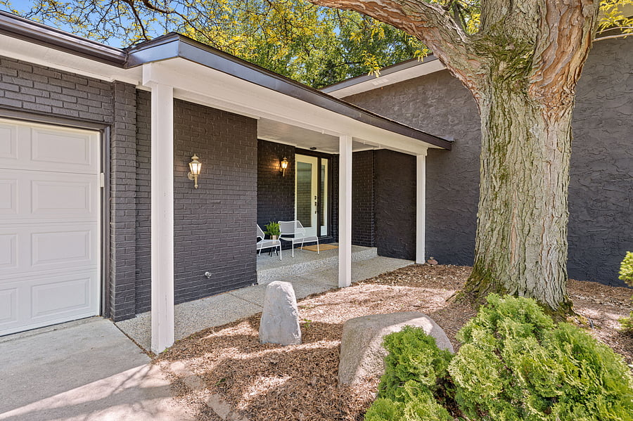 Front entry porch with mature shade trees and accent lighting.