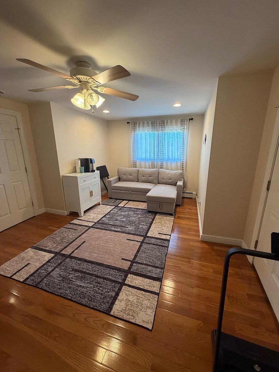 Living room with coffee maker, couch, tv, microwave, and mini fridge.
