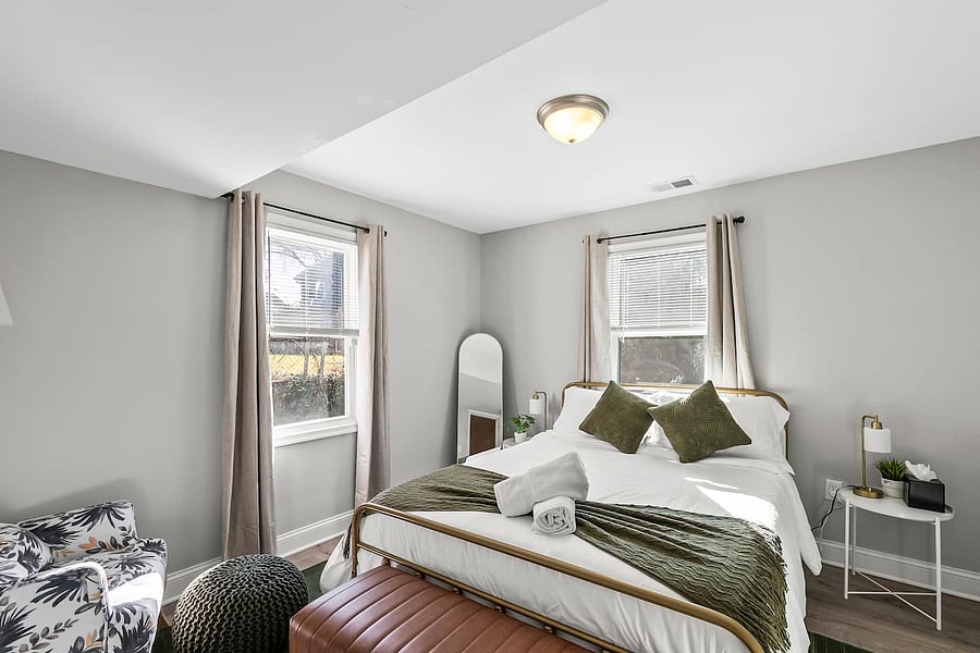 Relax in a bedroom with a new Queen bed, premium bedding, accent chairs with Ottoman, full-length mirrors, nightstands with charging ports, spacious closet with hangers, and blackout curtains for a perfect night's sleep.