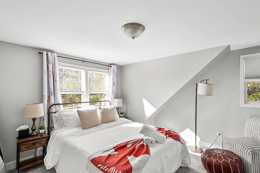 Rest easy in a bedroom with a Queen bed, premium bedding, comfy accent chairs & Ottoman, full-length mirror, nightstands with charging ports, closet, blackout curtains, and smart TV.