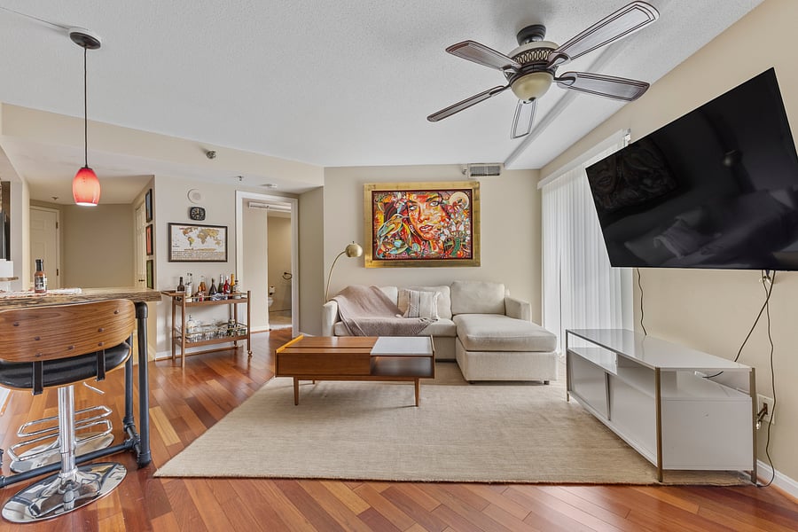 Spacious living area with a sectional sofa, ceiling fan, and wall-mounted Smart TV