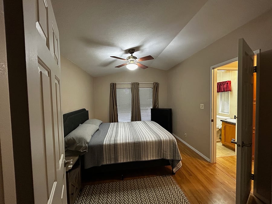 The second bedroom is next to the second bathroom. The window also has blinds and room-darkening curtains. A full-length mirror is also in the corner, but it's not in this photo.