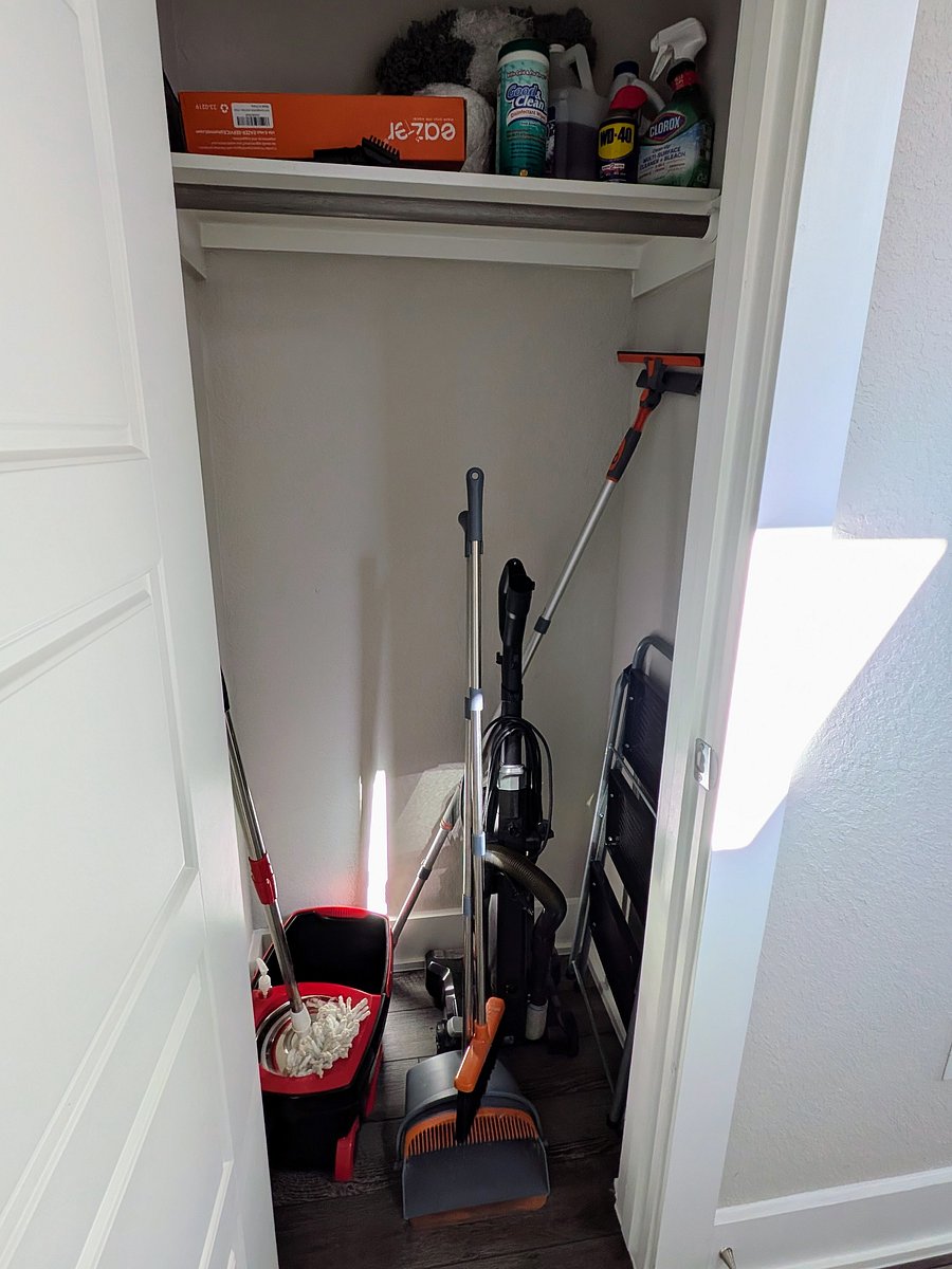 Utility closet with vacuum, mop, a step stool